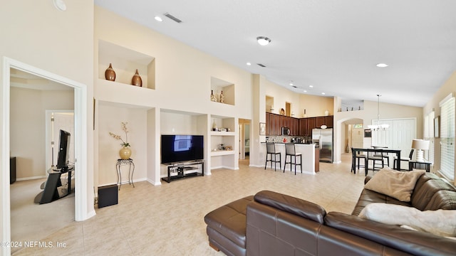 tiled living room featuring built in features, high vaulted ceiling, and a chandelier