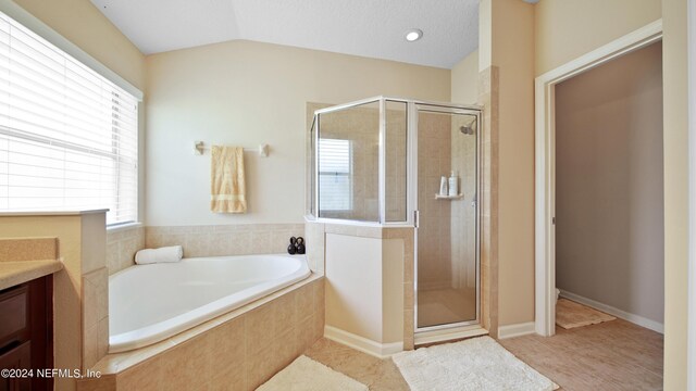 bathroom with tile floors, vanity, shower with separate bathtub, and vaulted ceiling