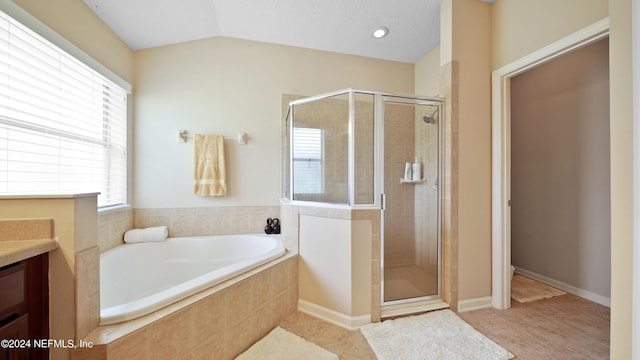 bathroom with tile floors, vanity, shower with separate bathtub, and vaulted ceiling