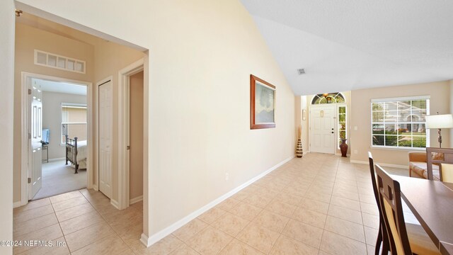 corridor with vaulted ceiling and light tile flooring