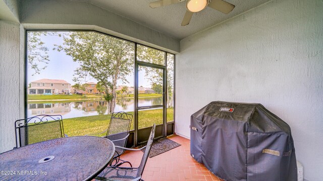 sunroom / solarium with ceiling fan and a water view