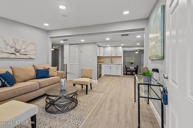 living room with ceiling fan, light hardwood / wood-style flooring, and sink