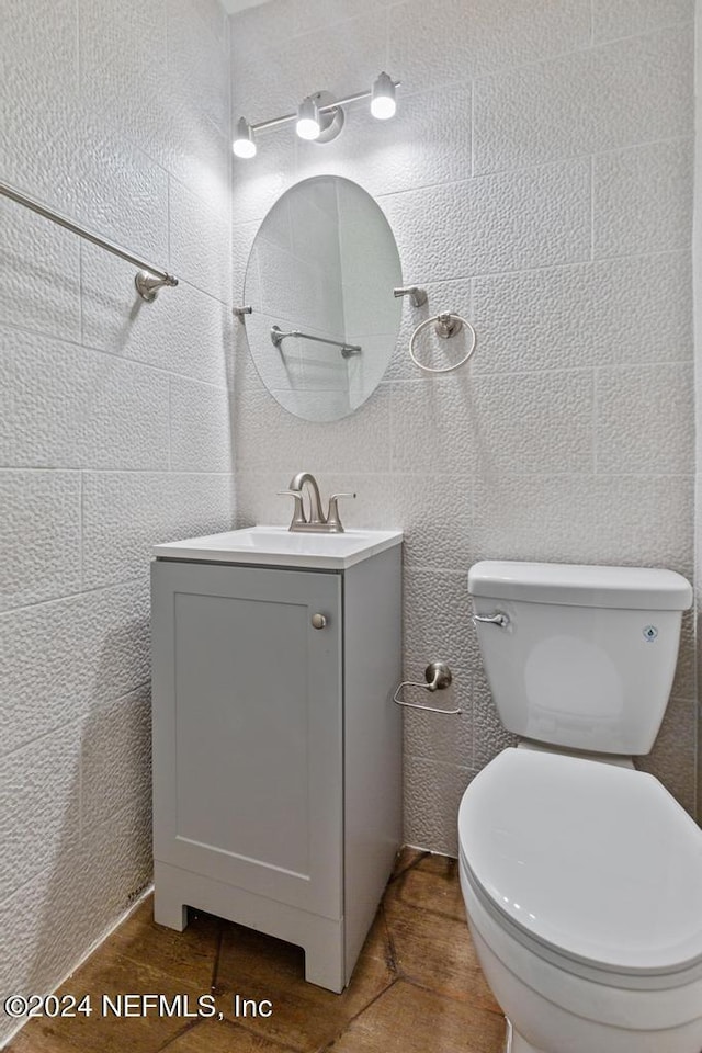 bathroom featuring vanity, toilet, and tile walls