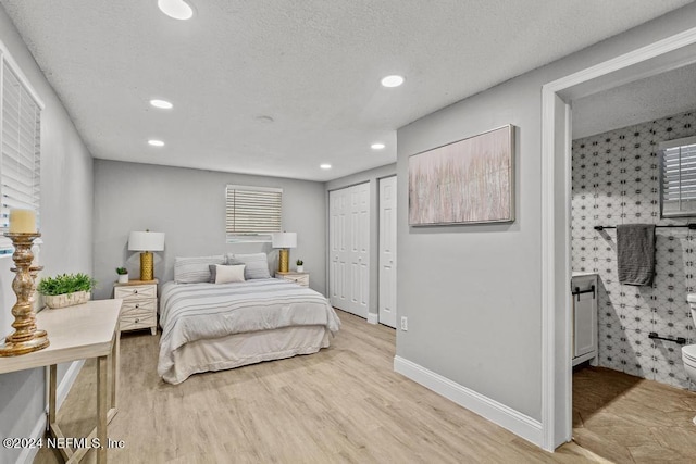 bedroom with light hardwood / wood-style floors, a textured ceiling, and a closet