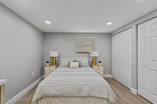 bedroom featuring light hardwood / wood-style floors and multiple closets