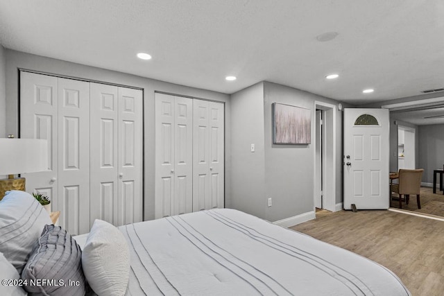 bedroom with light hardwood / wood-style flooring and two closets