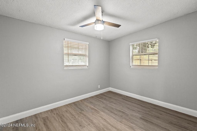 unfurnished room with a wealth of natural light, hardwood / wood-style floors, and a textured ceiling