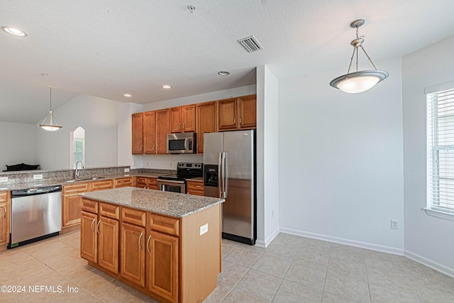 kitchen with light stone countertops, pendant lighting, appliances with stainless steel finishes, and a kitchen island