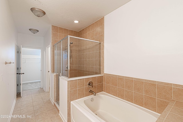 bathroom with plus walk in shower, a textured ceiling, and tile patterned flooring