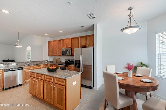 kitchen with pendant lighting, a kitchen island, appliances with stainless steel finishes, and light tile patterned flooring