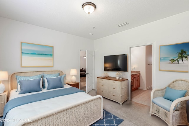 bedroom featuring ensuite bathroom and light carpet