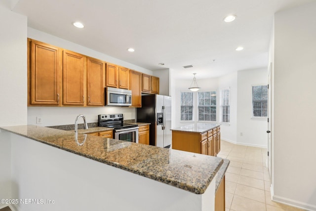 kitchen featuring dark stone countertops, kitchen peninsula, and appliances with stainless steel finishes