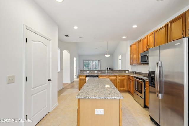 kitchen with kitchen peninsula, sink, decorative light fixtures, a kitchen island, and stainless steel appliances