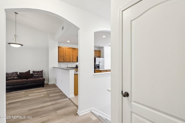 kitchen with sink, decorative light fixtures, light hardwood / wood-style floors, and stainless steel fridge