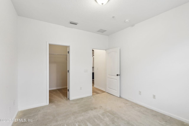 unfurnished bedroom featuring light carpet, a closet, and a walk in closet