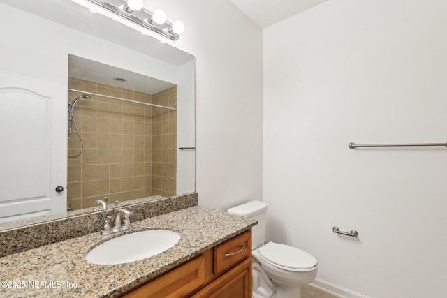 bathroom featuring toilet, vanity, and tiled shower