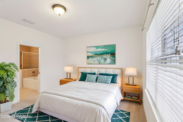 bedroom featuring ensuite bathroom and light carpet