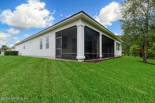 back of house featuring a yard and a sunroom