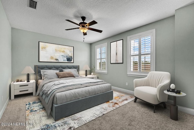 carpeted bedroom with ceiling fan and a textured ceiling