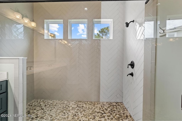 bathroom with tiled shower and vanity