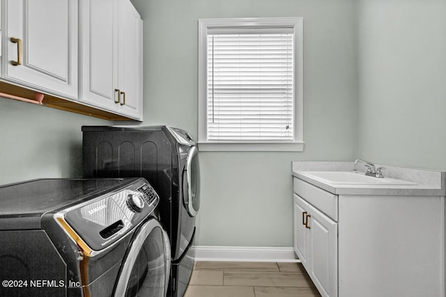 laundry area featuring cabinets, sink, washer and dryer, and light wood-type flooring