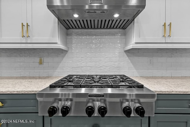 kitchen with stainless steel gas stovetop, wall chimney exhaust hood, white cabinetry, and backsplash