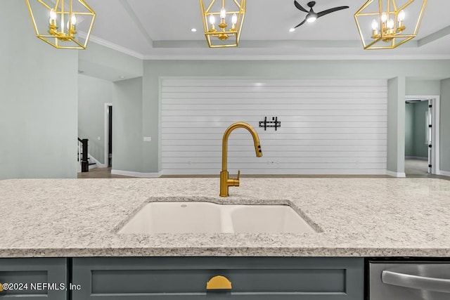 kitchen featuring light stone counters, sink, crown molding, and decorative light fixtures