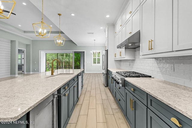 kitchen featuring a kitchen island with sink, white cabinets, hanging light fixtures, sink, and appliances with stainless steel finishes