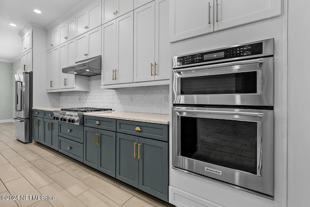 kitchen featuring tasteful backsplash, light stone counters, ornamental molding, stainless steel appliances, and white cabinets