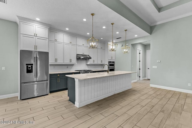 kitchen with stainless steel appliances, sink, decorative light fixtures, a center island with sink, and white cabinetry