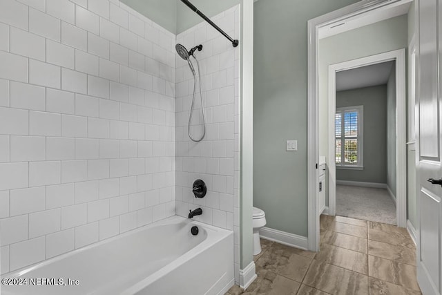 bathroom with tile patterned floors, tiled shower / bath combo, and toilet