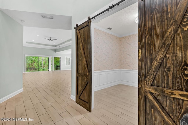 interior space with a barn door and a tray ceiling