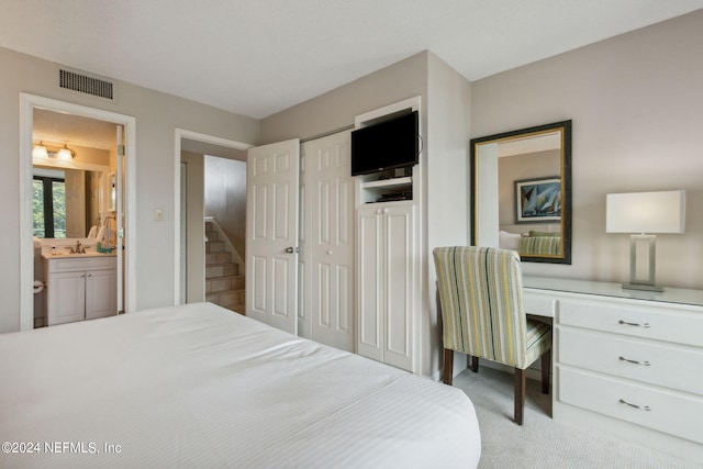 carpeted bedroom with sink and ensuite bath