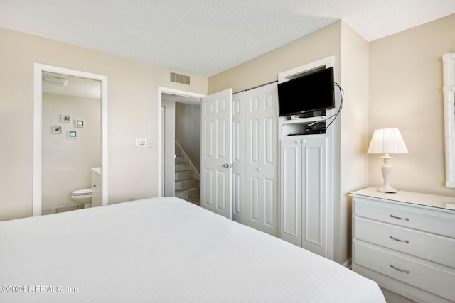 bedroom featuring ensuite bathroom and a textured ceiling