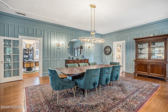 dining area featuring an inviting chandelier, ornamental molding, and hardwood / wood-style flooring