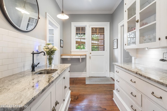 kitchen with light stone countertops, tasteful backsplash, pendant lighting, dark hardwood / wood-style flooring, and white cabinets