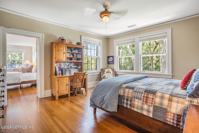 bedroom with ornamental molding, ceiling fan, and light wood-type flooring