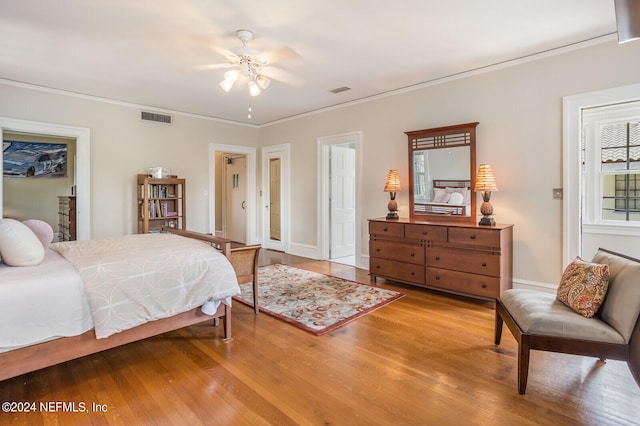 bedroom with ornamental molding, wood-type flooring, and ceiling fan