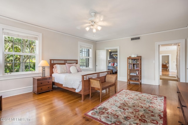 bedroom with a spacious closet, ceiling fan, ornamental molding, and wood-type flooring