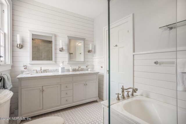 bathroom featuring double vanity, a washtub, wooden walls, and tile floors