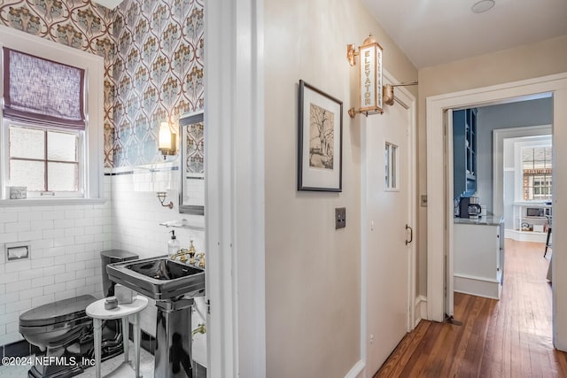 corridor featuring dark wood-type flooring, plenty of natural light, and tile walls