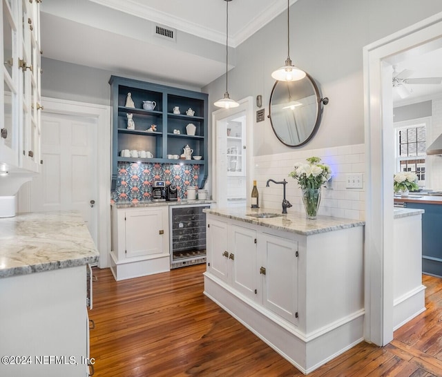 kitchen with beverage cooler, hardwood / wood-style flooring, white cabinetry, and backsplash