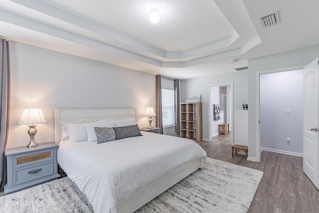 bedroom with a tray ceiling and hardwood / wood-style floors