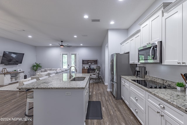 kitchen with black electric cooktop, sink, a center island with sink, dark wood-type flooring, and ceiling fan