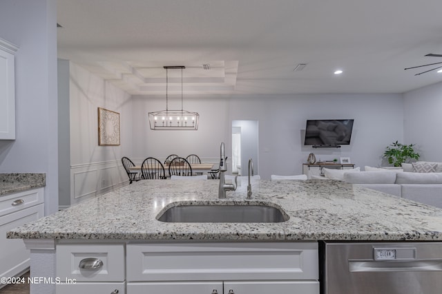 kitchen with sink, white cabinets, ceiling fan with notable chandelier, and light stone countertops