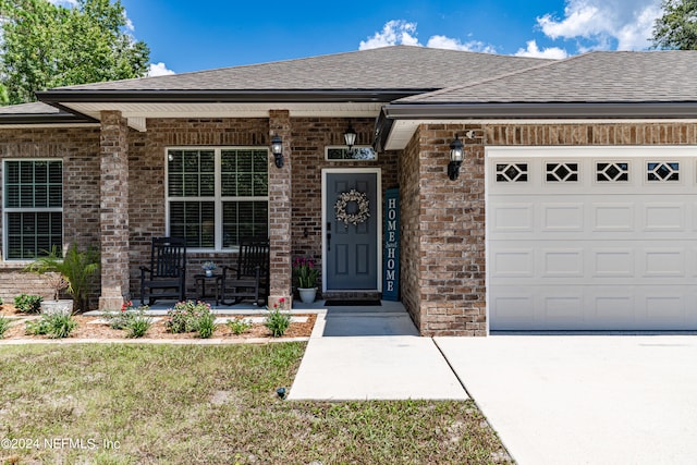 view of exterior entry with a garage and a yard