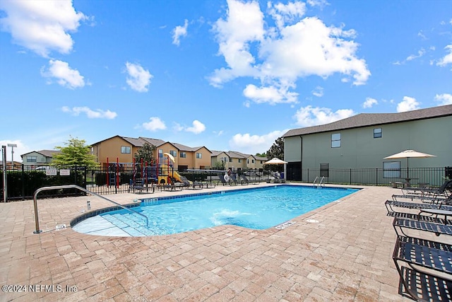 view of pool featuring a playground and a patio