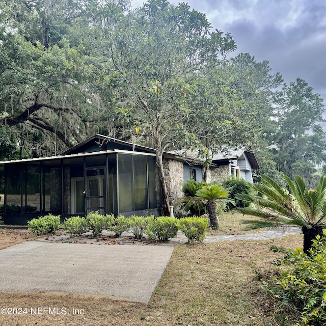 view of front of house featuring stone siding and a sunroom