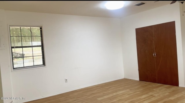 spare room featuring visible vents, light wood-style flooring, and baseboards