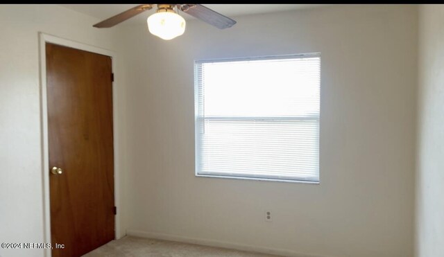 empty room featuring light colored carpet, ceiling fan, and baseboards